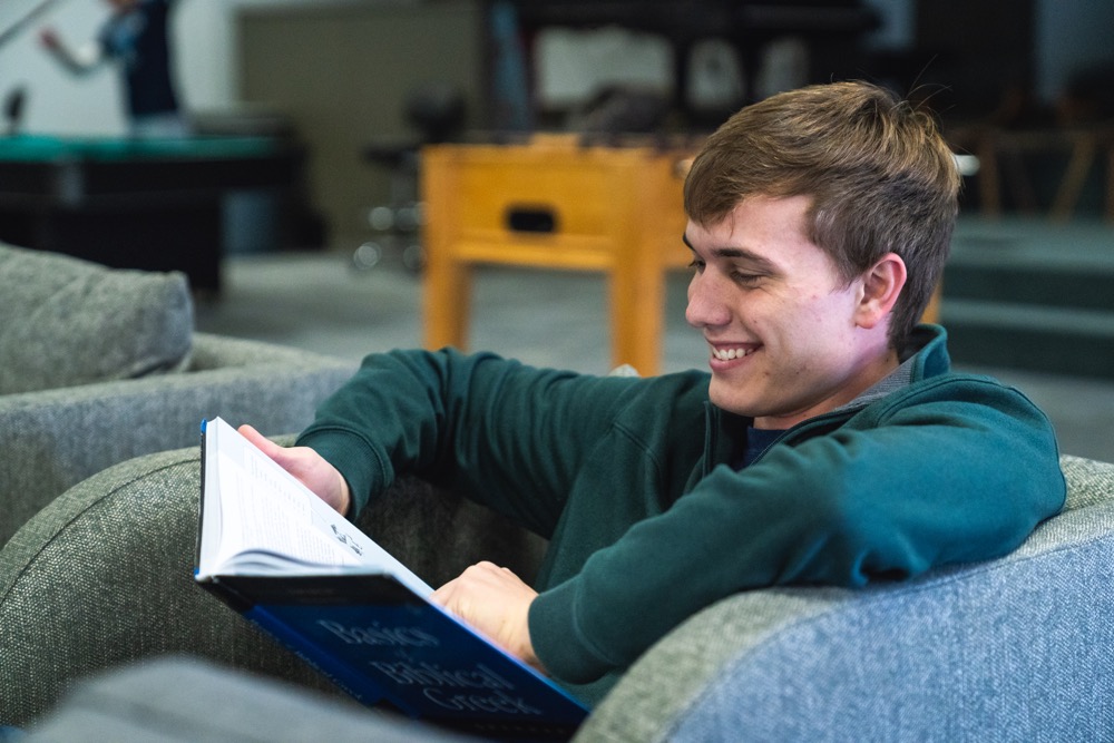College student reading textbook in chair