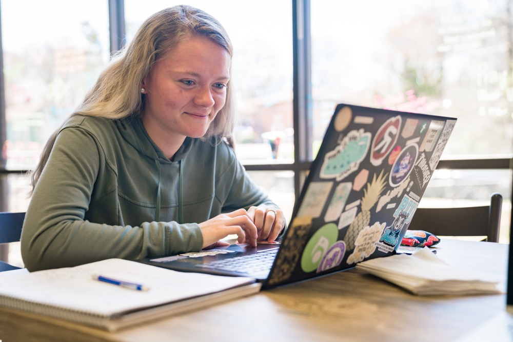 Girl sitting at table using laptop