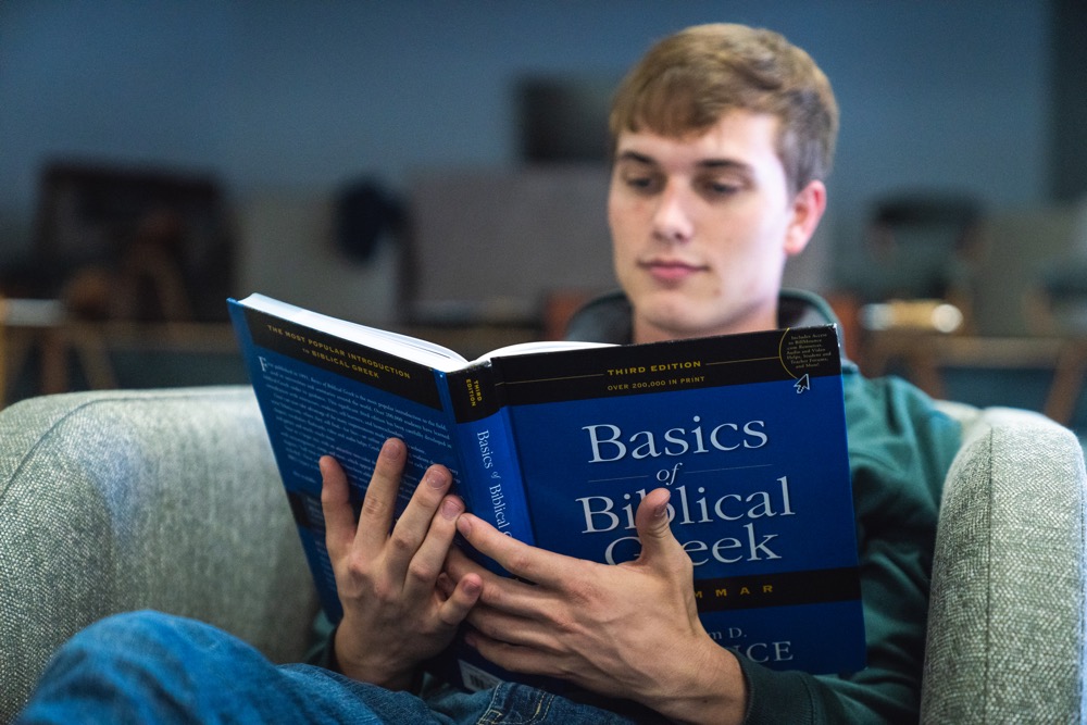 Student reading book in chair