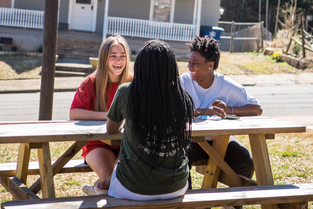 Three students sitting at a picnic table outside