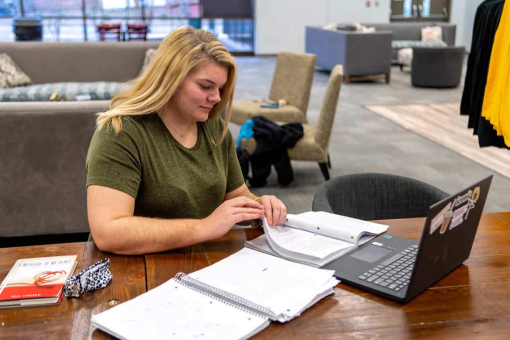 Student working on coursework at table in student center