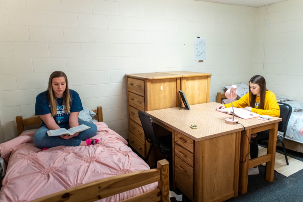 Two female college students studying in dorm room