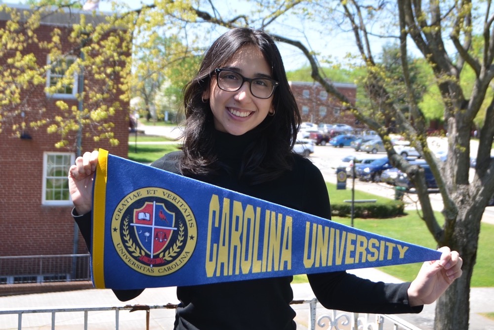 Student holding Carolina University pennant